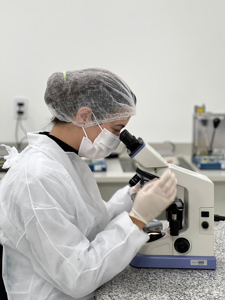 Cientista analisando amostras em microscópio de alta resolução no laboratório Axis Biotec